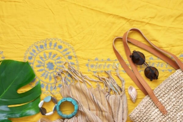 fular amarillo con bordado hippie en azul, gafas de sol boho, bolso de rafia para la playa