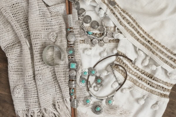 Fulares boho chic en blanco de distintas texturas y sobre ellos pendientes, collares y anillos plateados con piedras turquesas estilo bohemio hippie